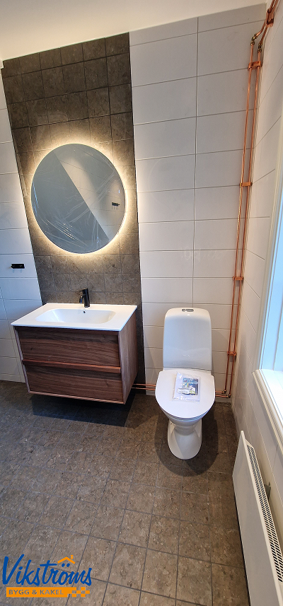 Toalett med helkaklade väggar – byggfirma i Uppsala har utfört en badrumsrenovering med fokus på kvalitet och hållbarhet.